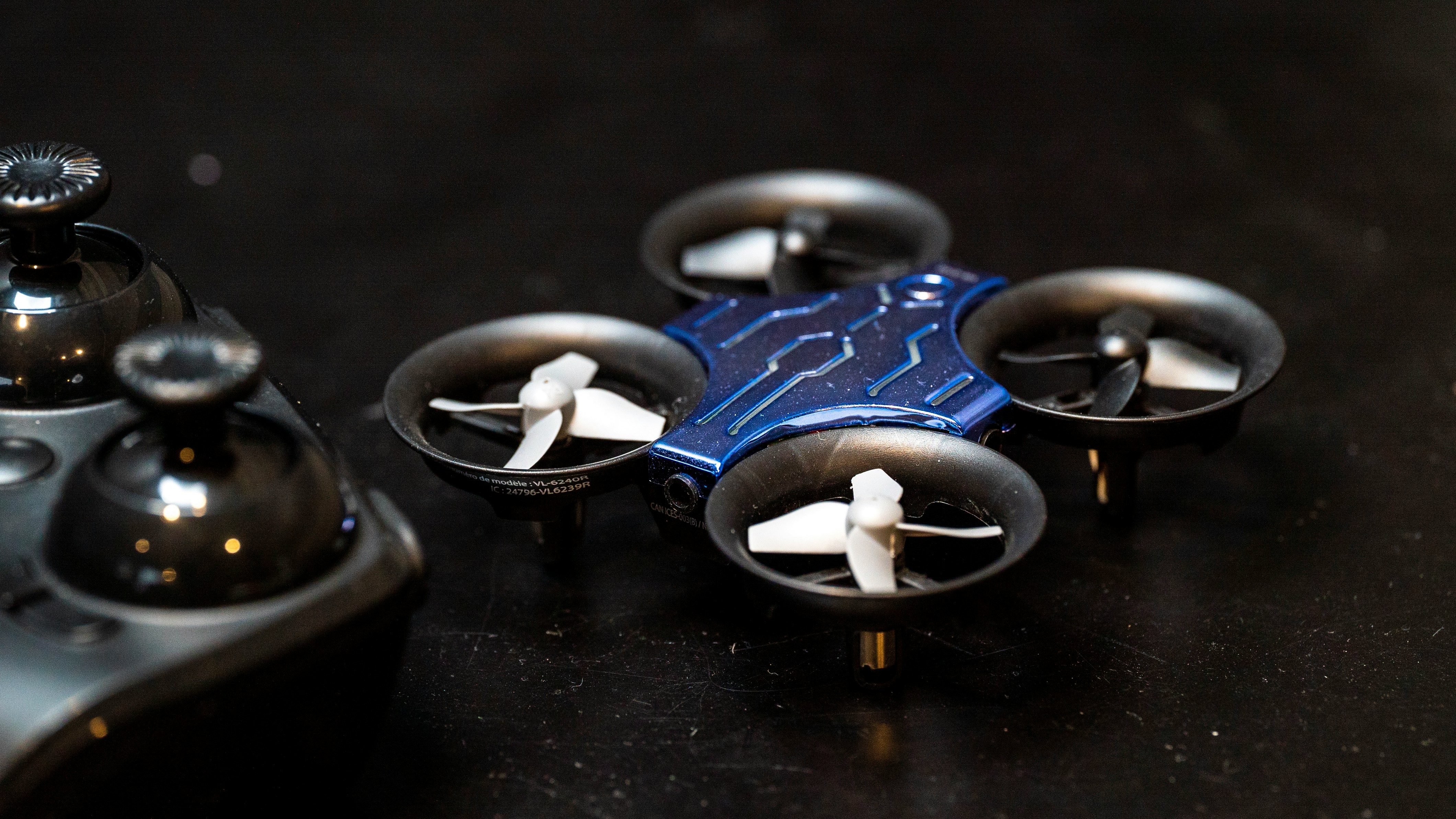 A sleek, futuristic, ultra-thin holographic tablet or high-end smartphone, levitating slightly above a glowing, minimalist geometric stand. The device screen displays a dynamic, abstract light pattern in electric blue and vivid violet, subtly animating. The background is a deep, ethereal digital void with subtle glowing particle effects and diffuse light rays emanating from behind the device. Hyper-realistic rendering, focus on polished dark surfaces, subtle reflections, and soft ambient light. No branding or text on the device. Style: Sci-fi, minimalist, ultra-modern, photorealistic rendering, 16:9 aspect ratio.